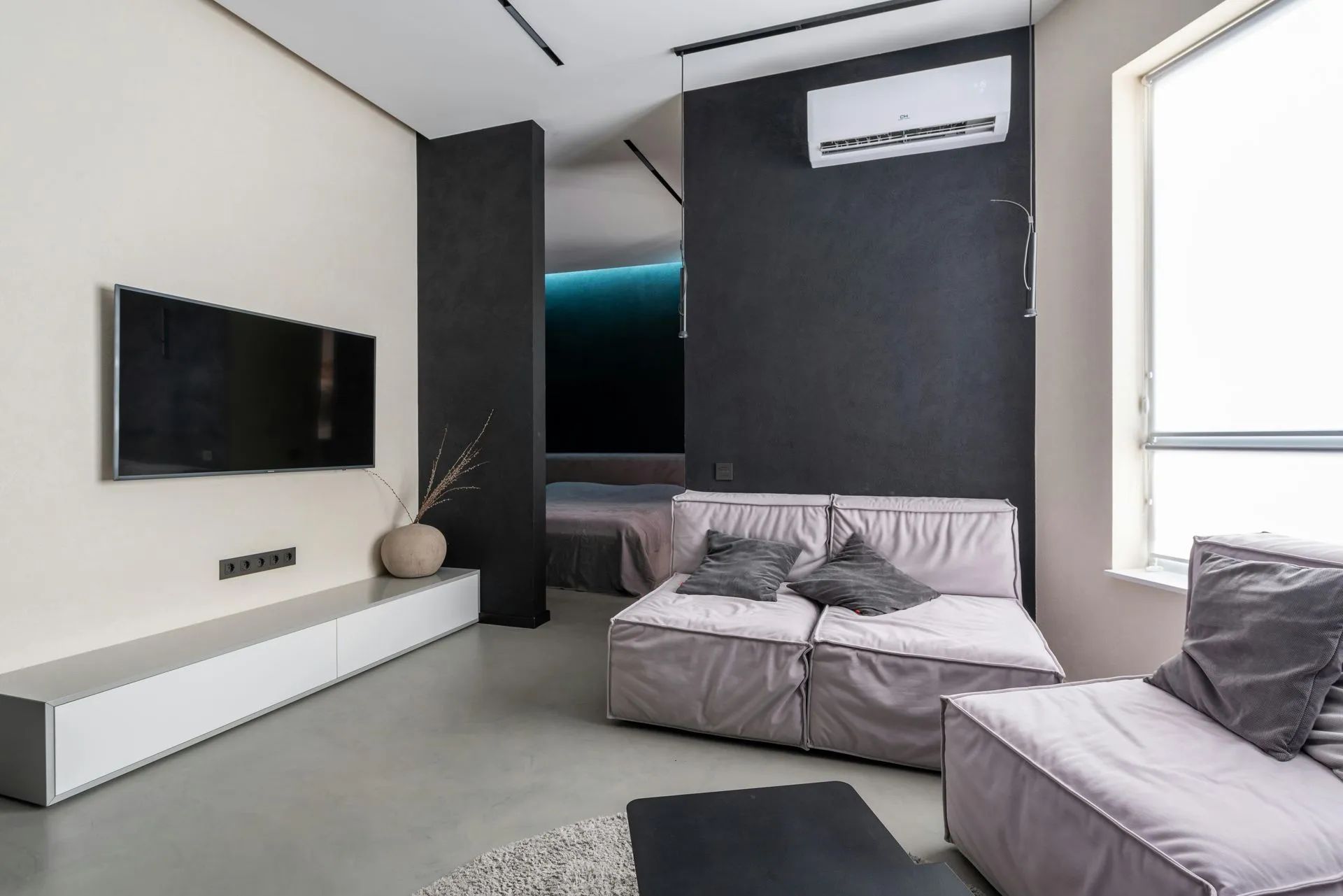 Modern living room with a TV, gray sofa, and minimalist decor.