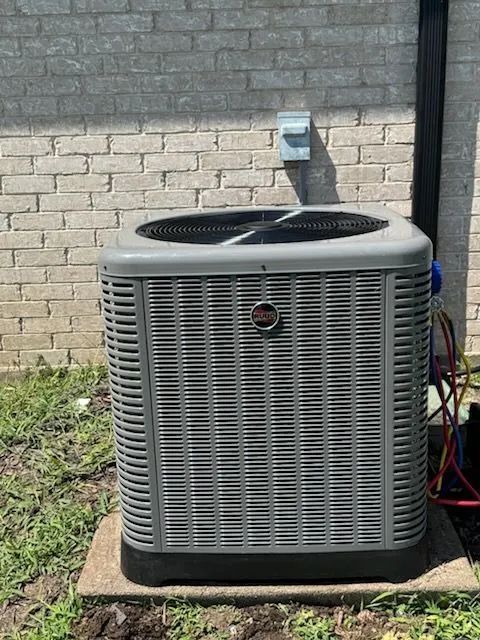 Air conditioning unit on concrete pad next to a brick wall.