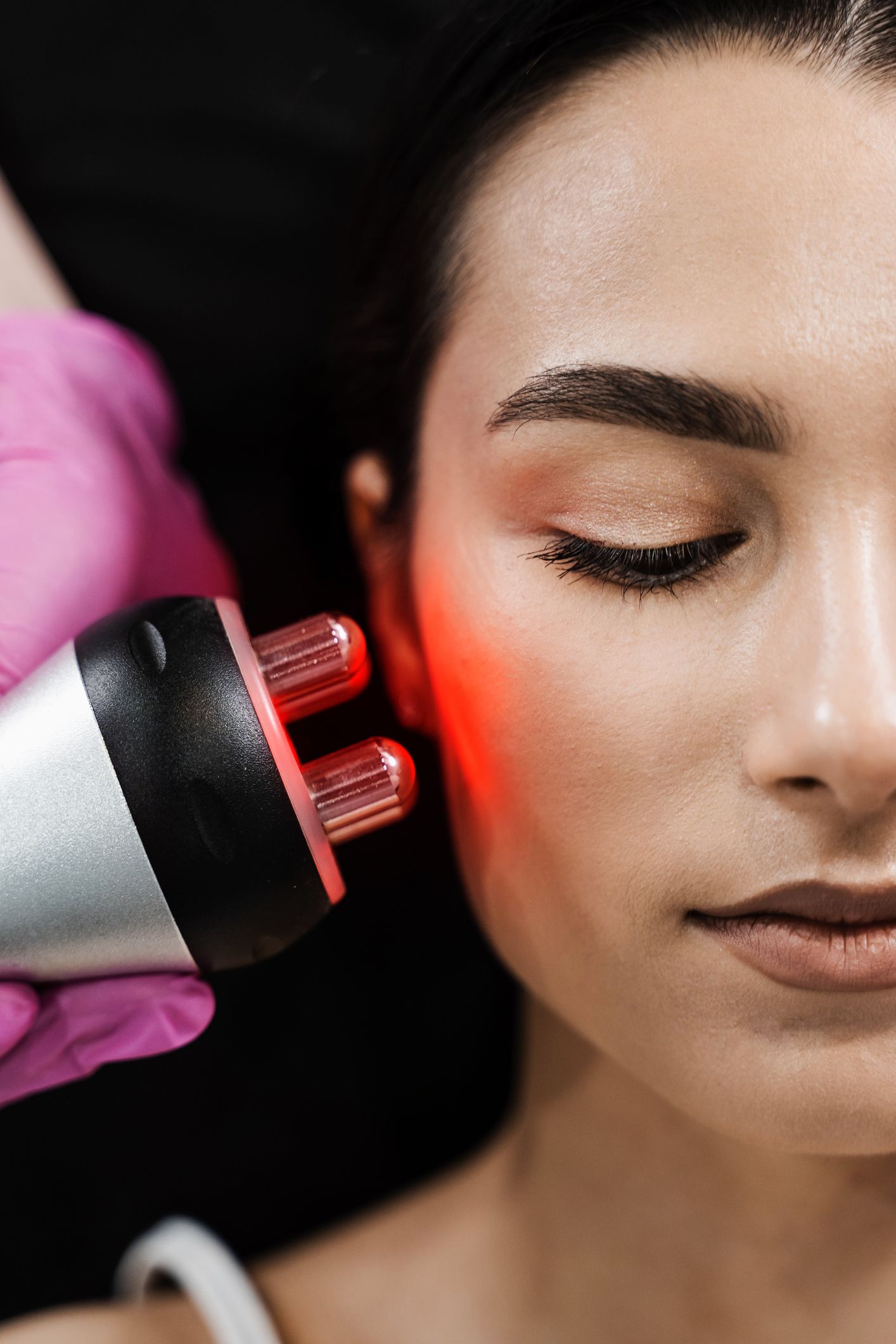 A woman is getting a red light treatment on her face.