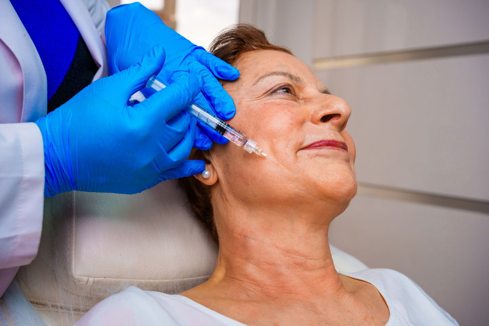 An older woman is getting a botox injection in her face.