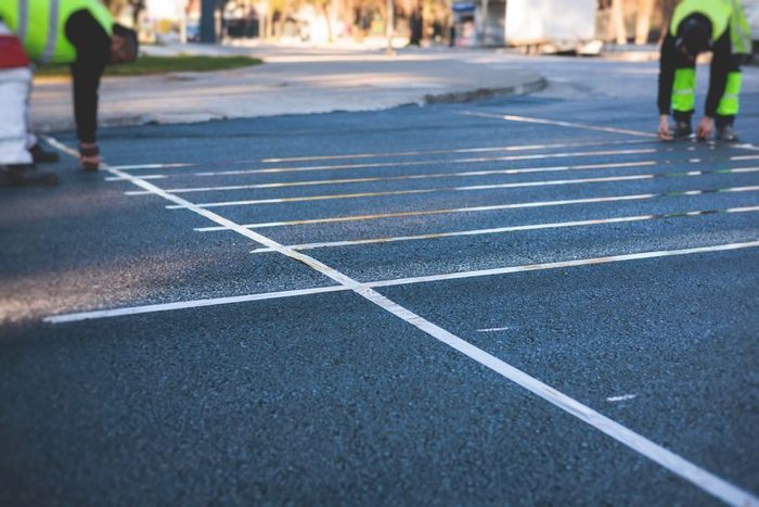Two men are painting white lines on the road.