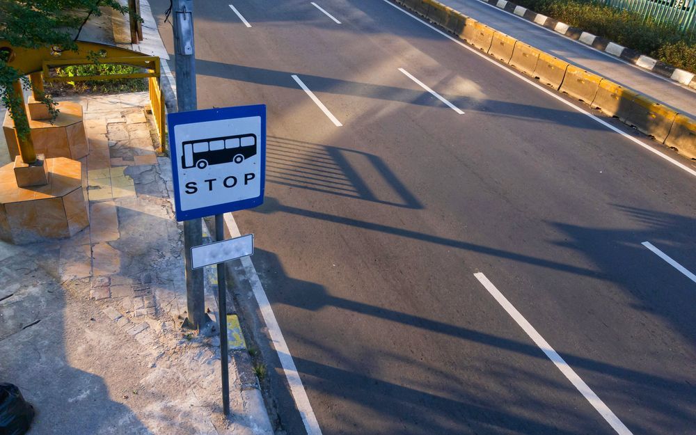 A bus stop sign on the side of a road