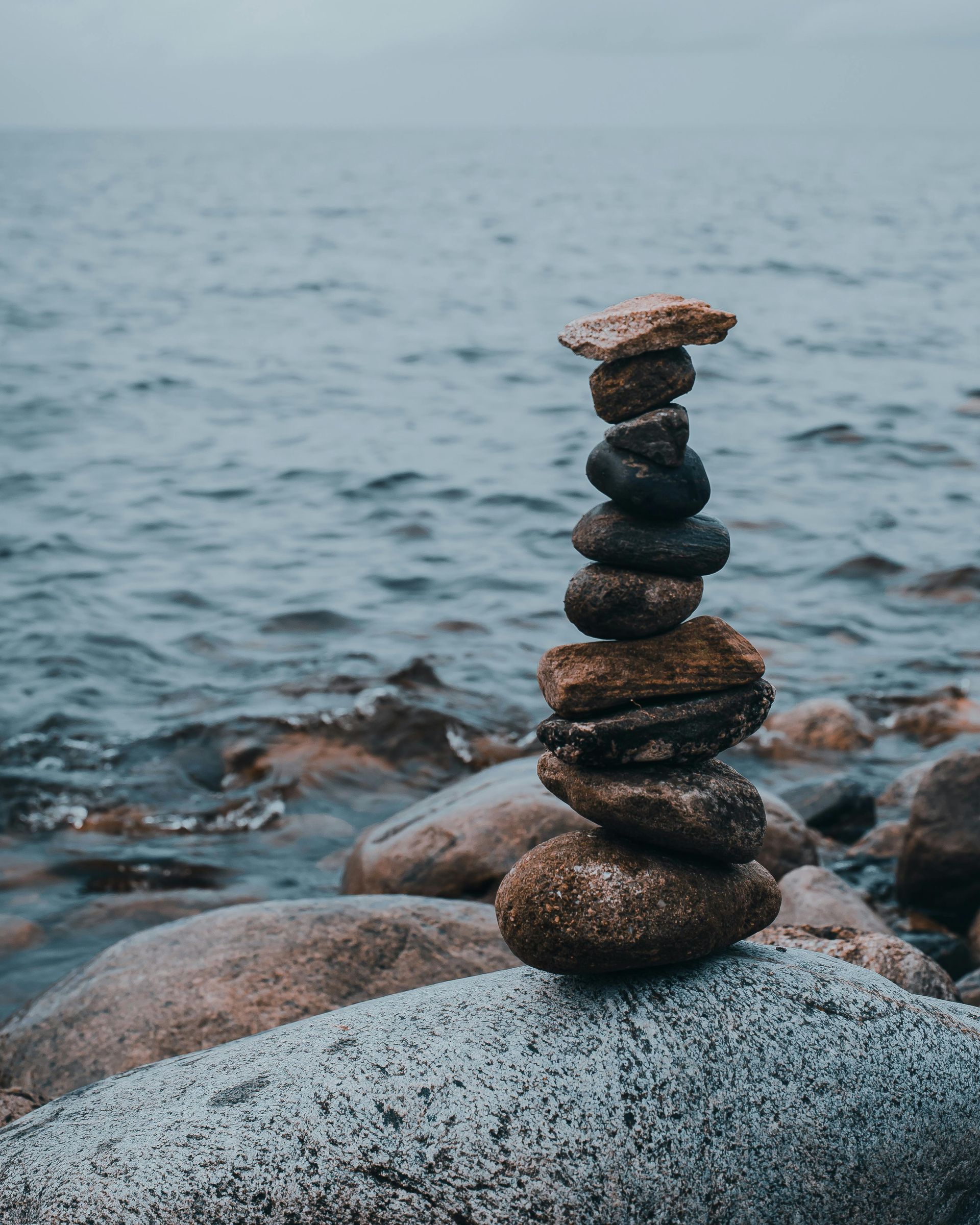 A pile of rocks stacked on top of each other on a rock near the ocean.