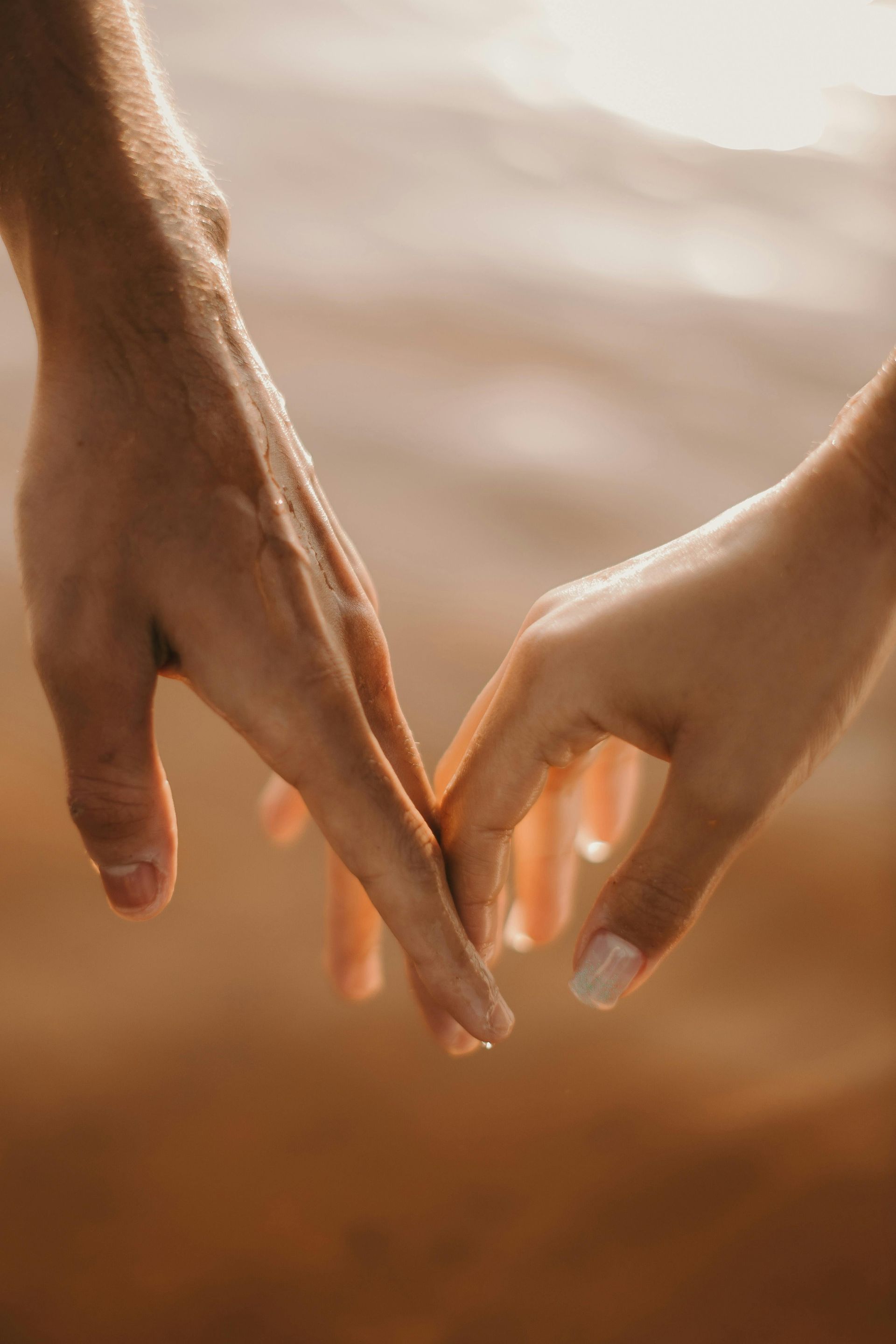 A man and a woman are holding hands in a heart shape.