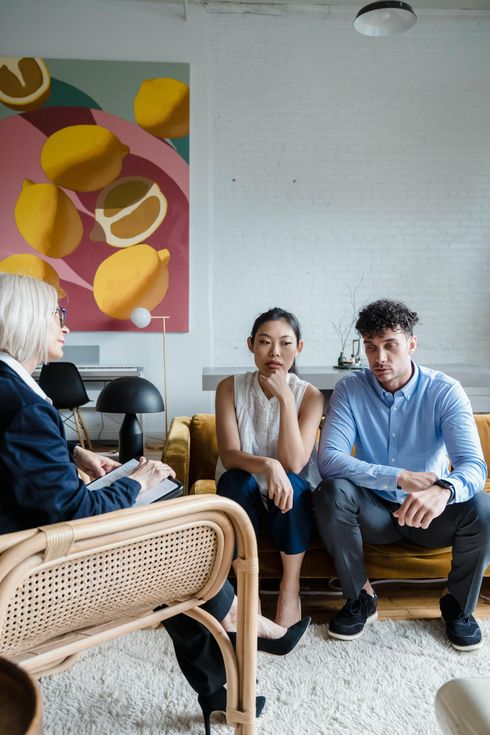 A man and a woman are sitting on a couch talking to a woman.