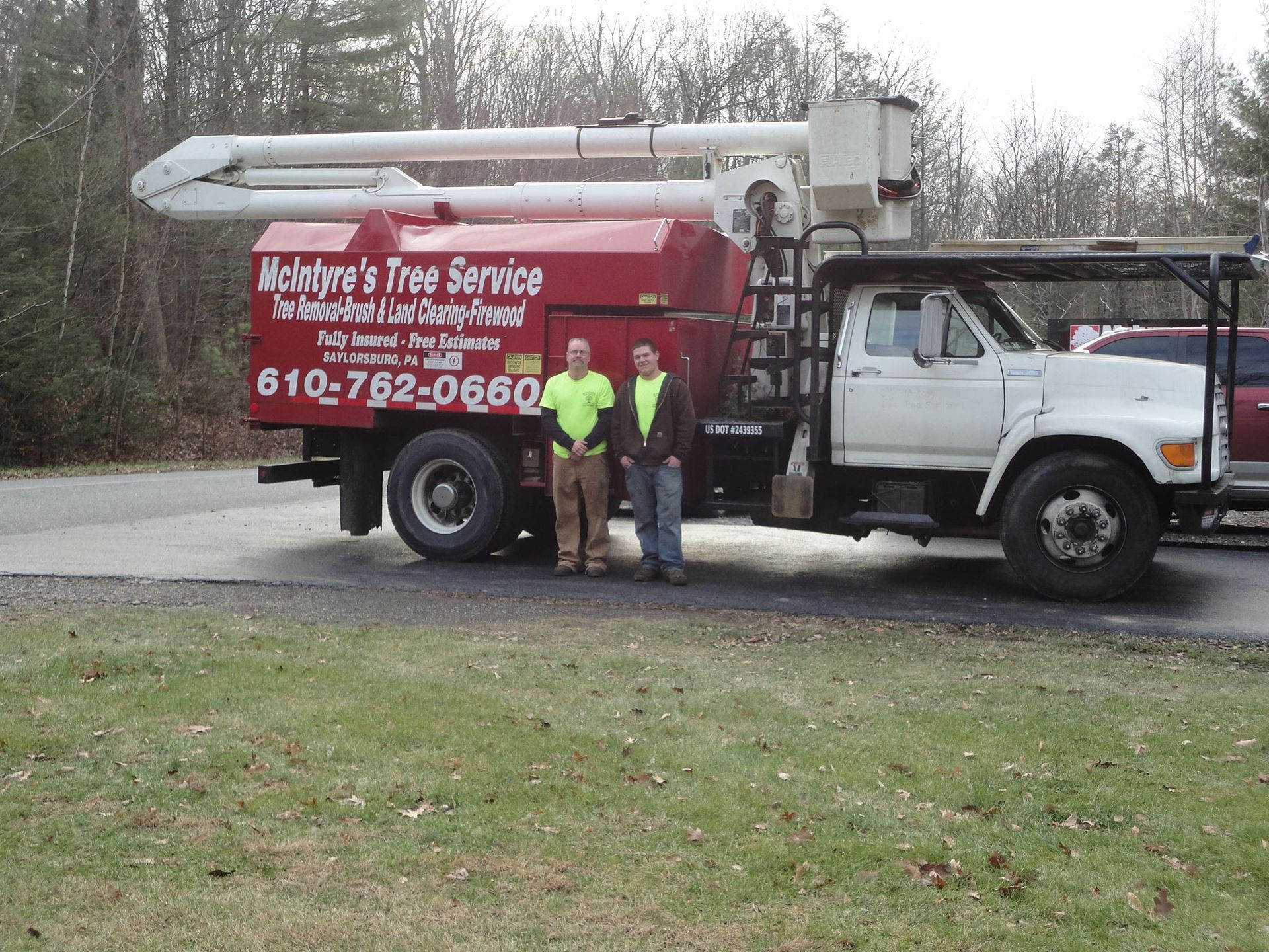 Two men standing in front of a mckinne 's tree service truck