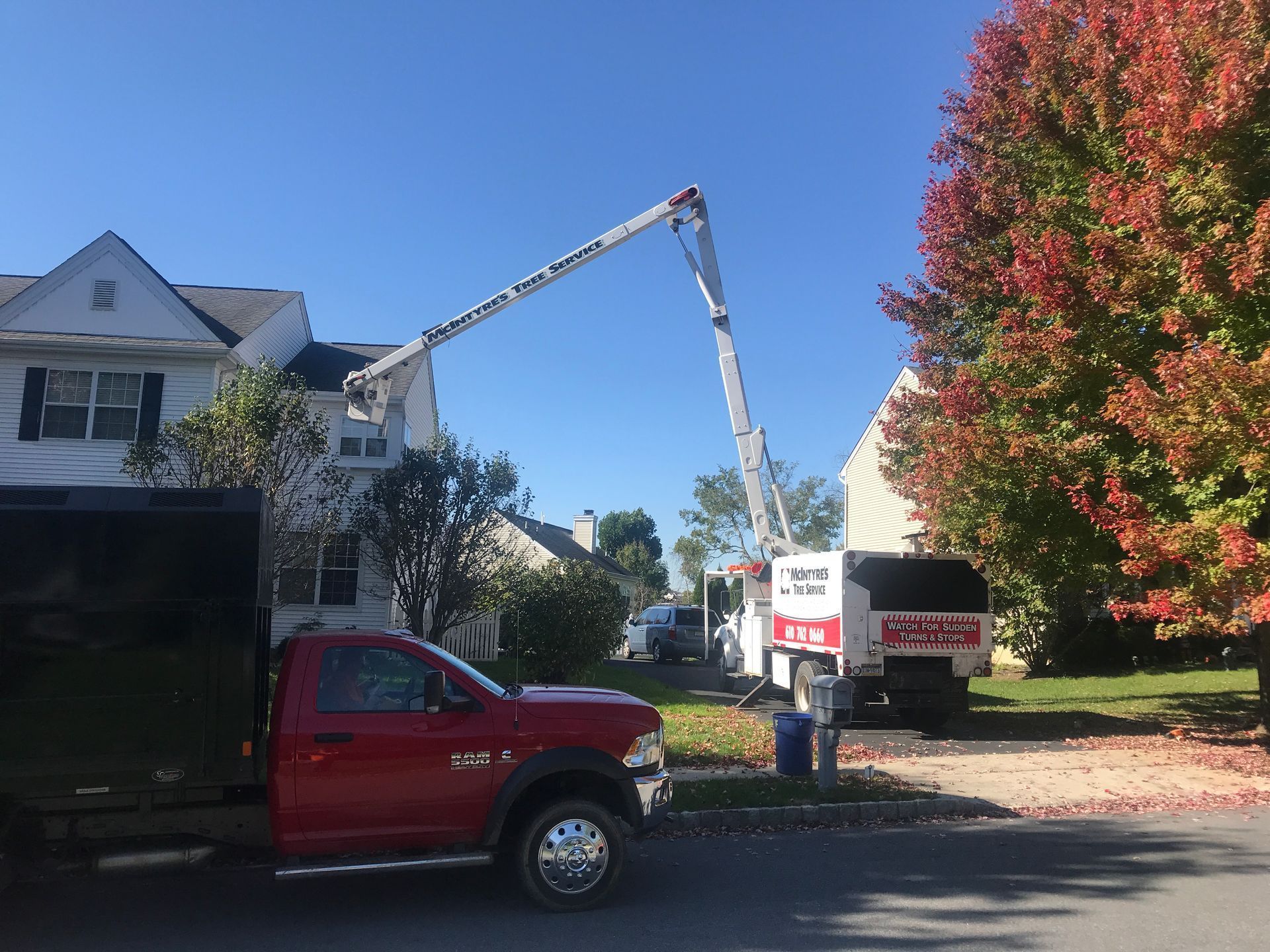 A red truck is parked in front of a house with a crane attached to it.