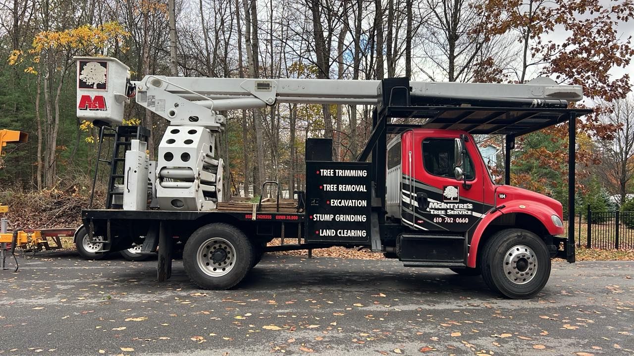 Red and black utility truck with an aerial lift, parked outdoors.