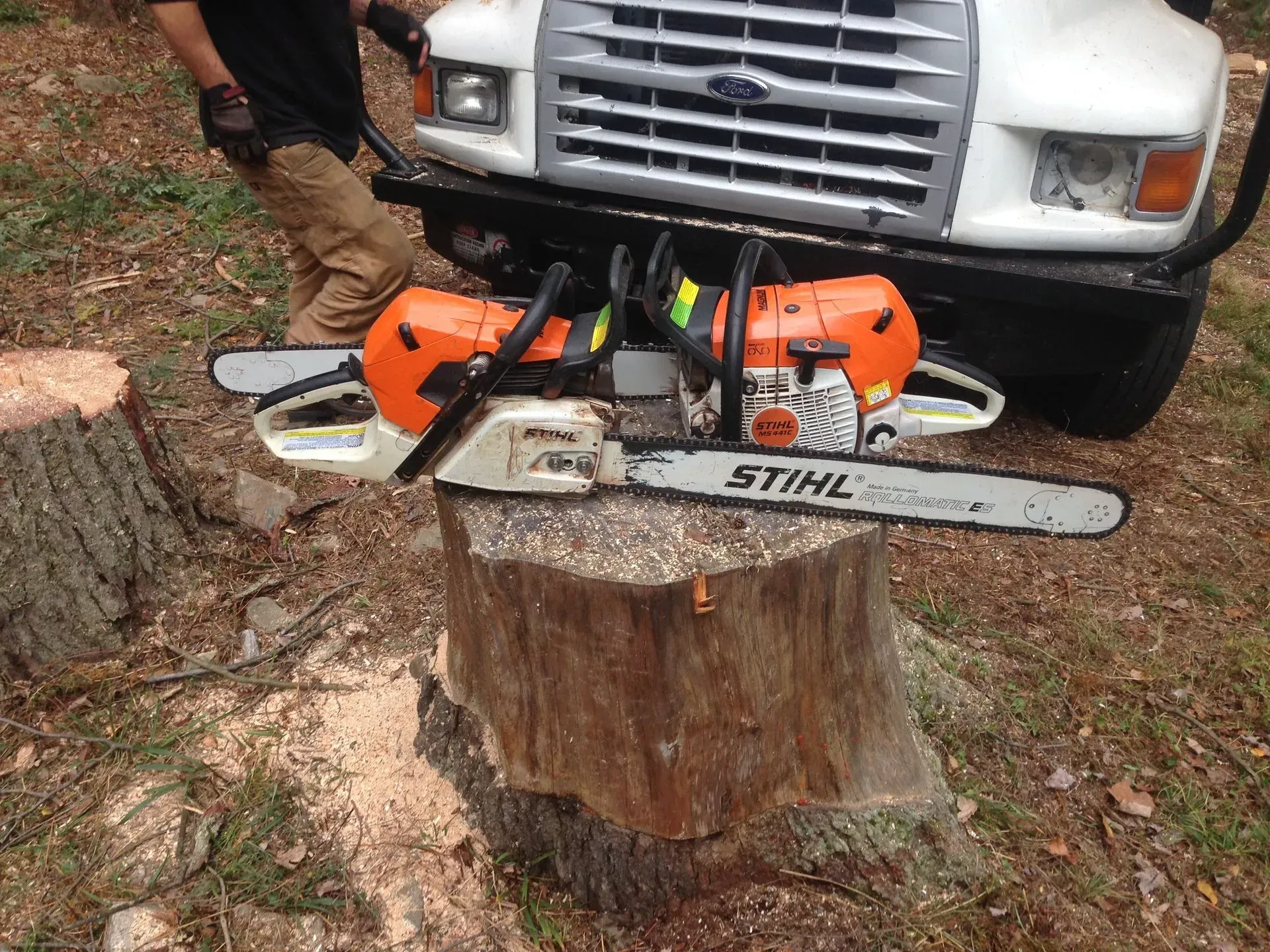 Two stihl chainsaws are sitting on top of a tree stump