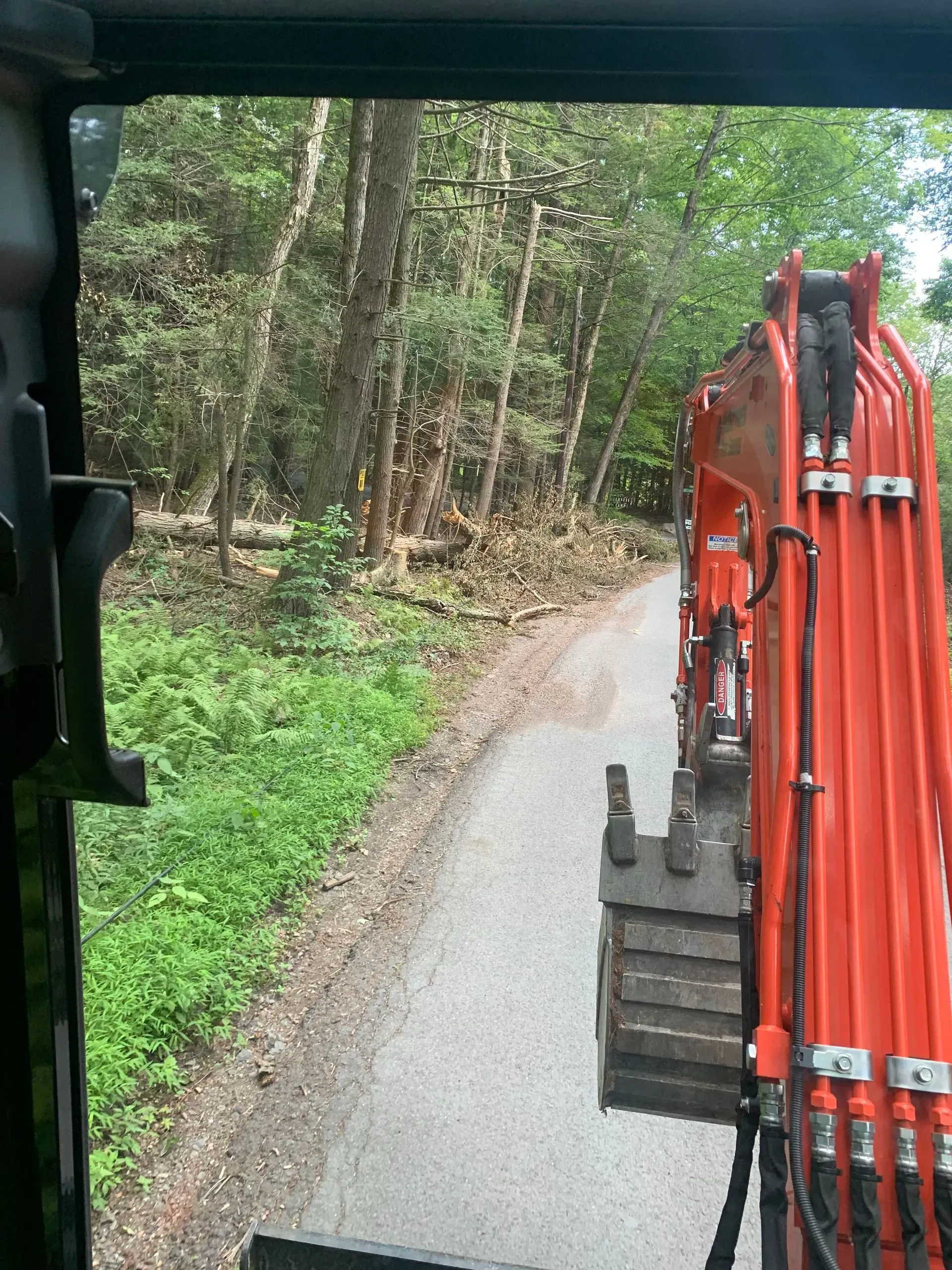 An excavator is driving down a dirt road in the woods