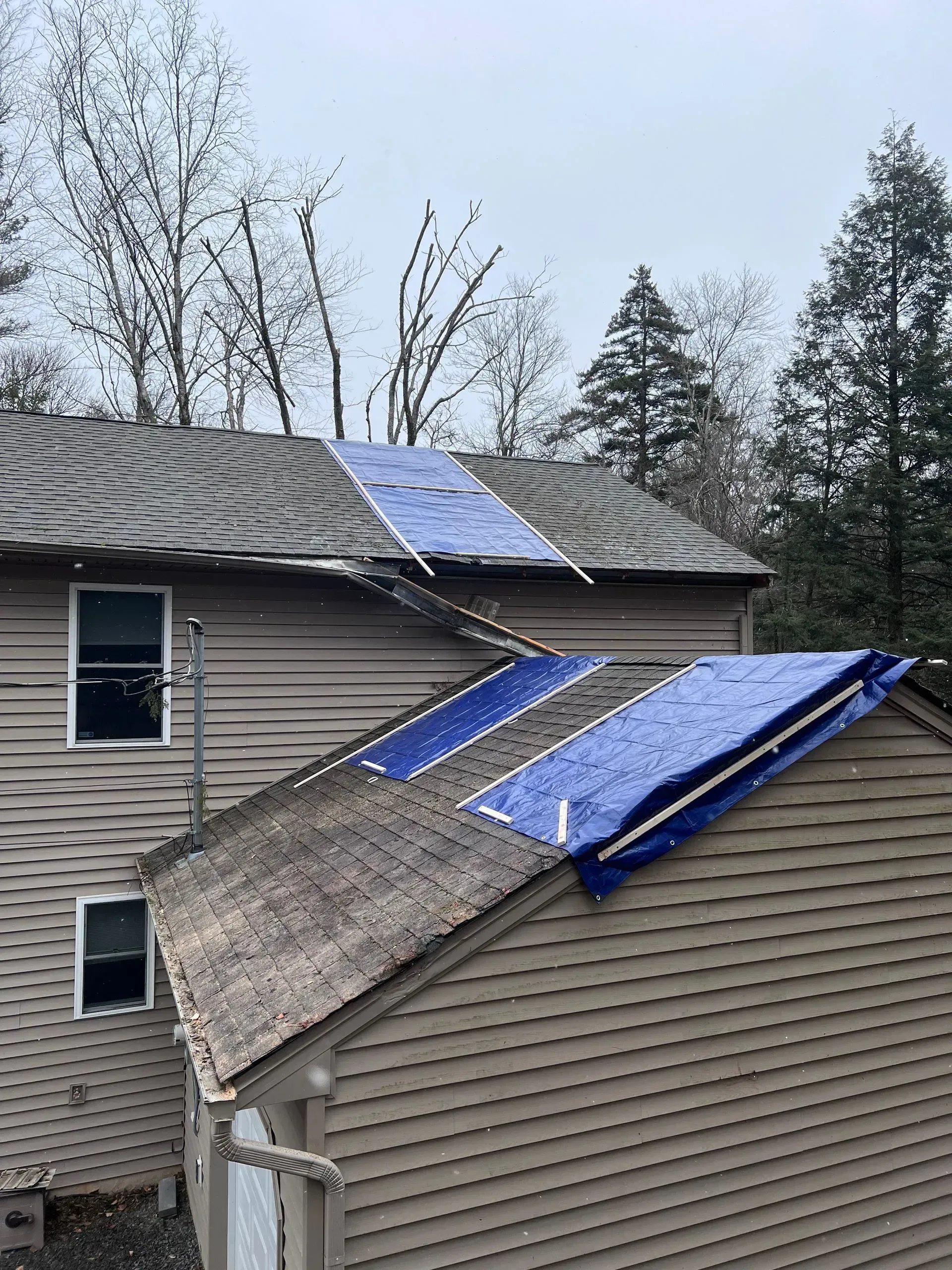 A house with a blue tarp on the roof.