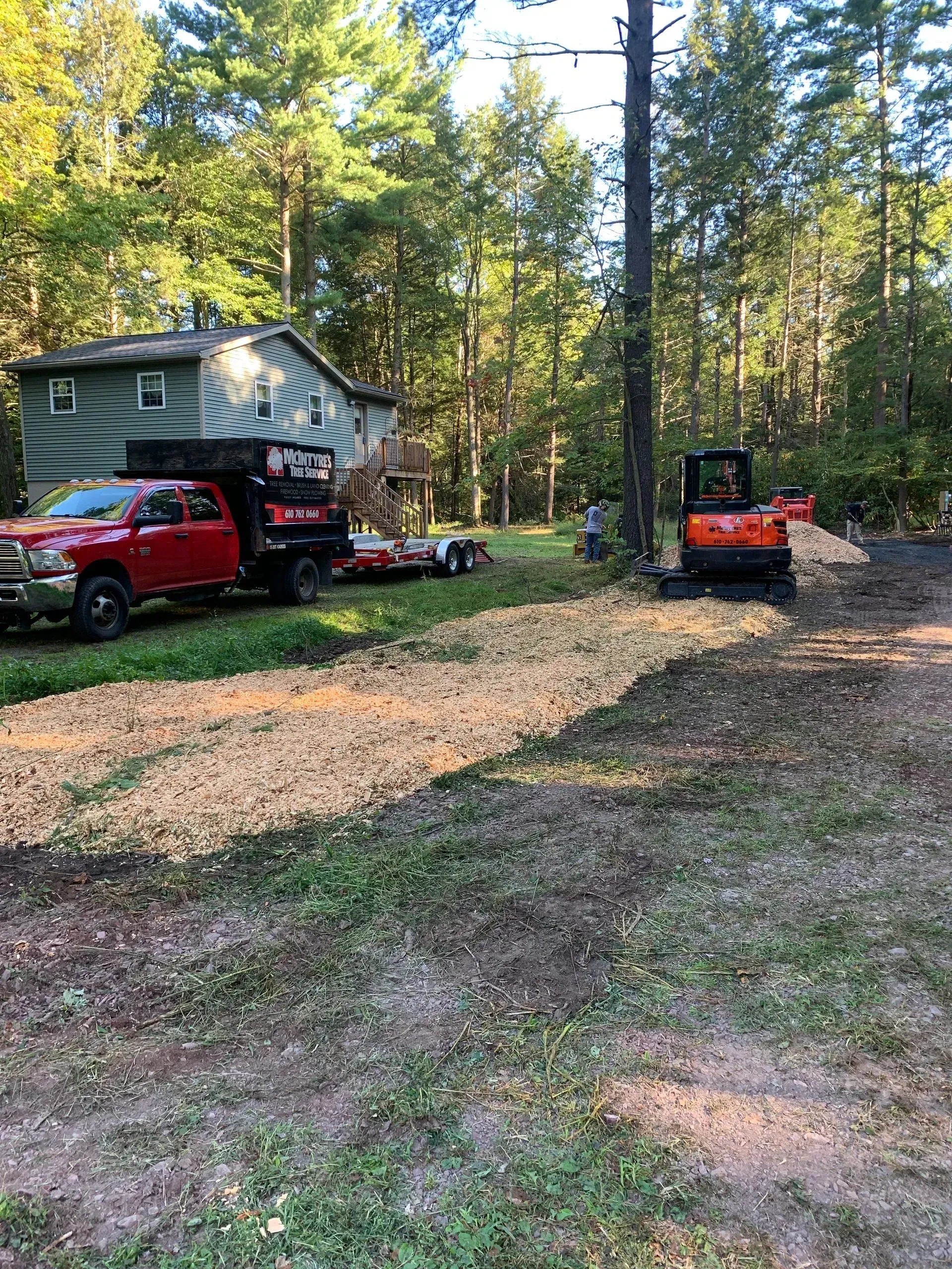 A red truck is parked in front of a house on a trailer.