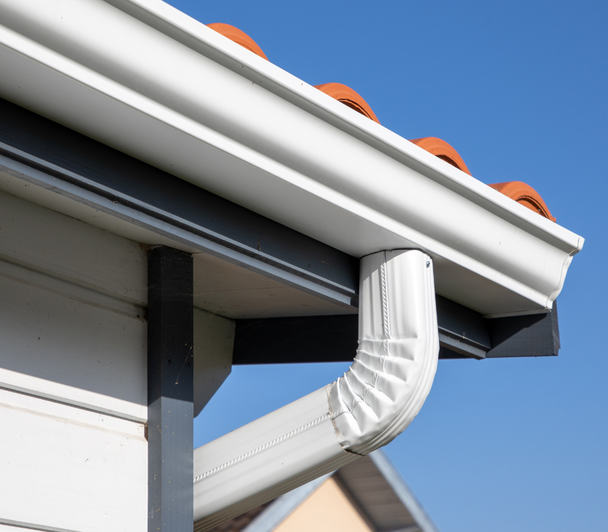A white gutter is attached to the roof of a house