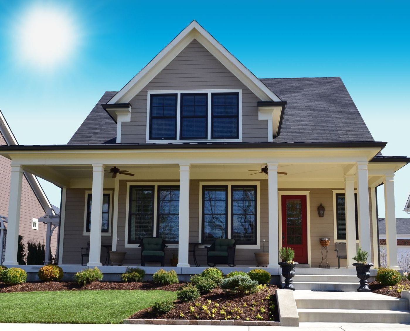 A house with a large porch and a red door