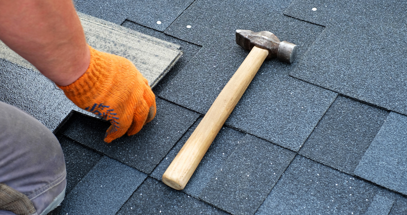 A person is installing shingles on a roof with a hammer.