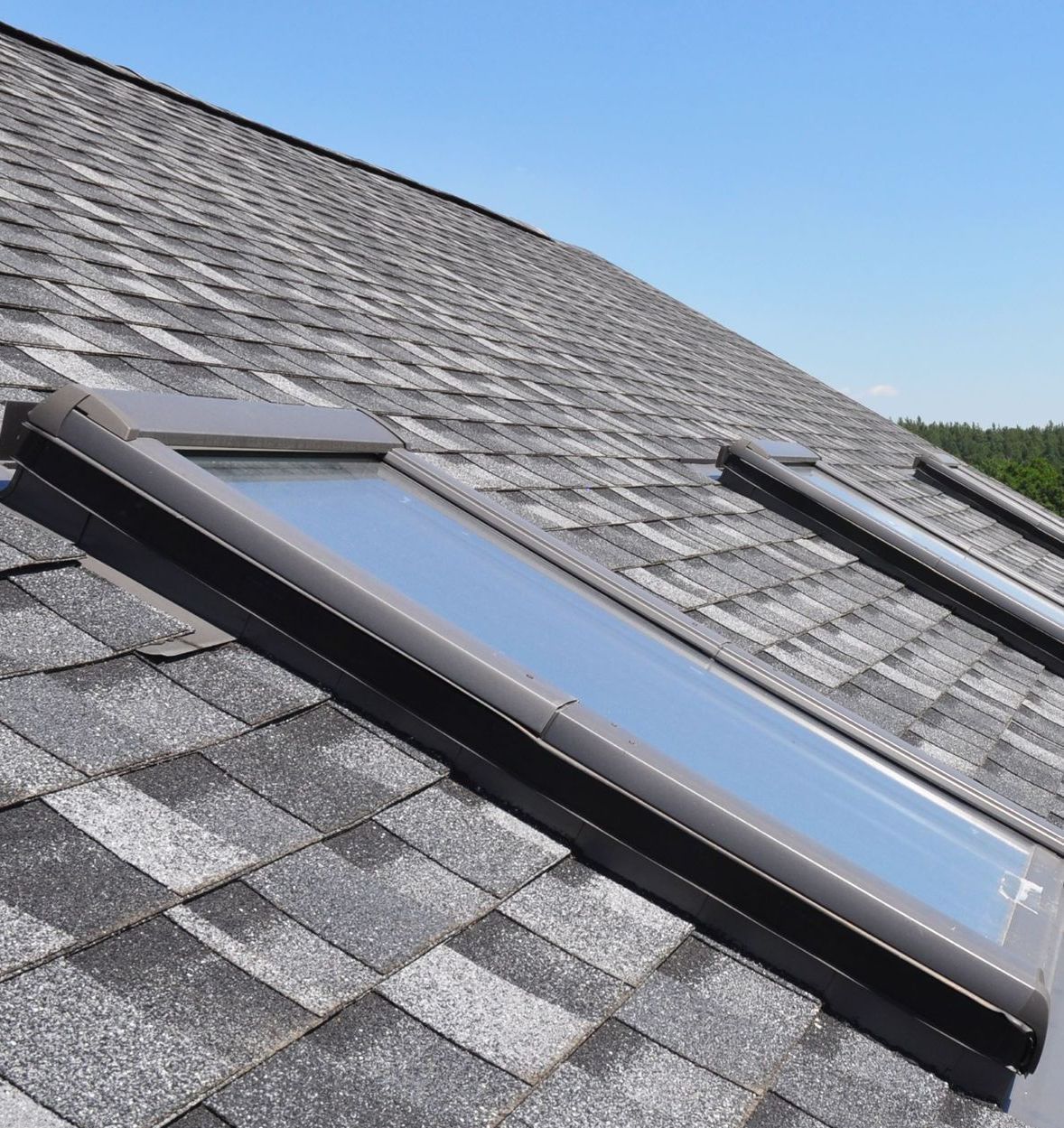 A roof with two skylights on it and a blue sky in the background