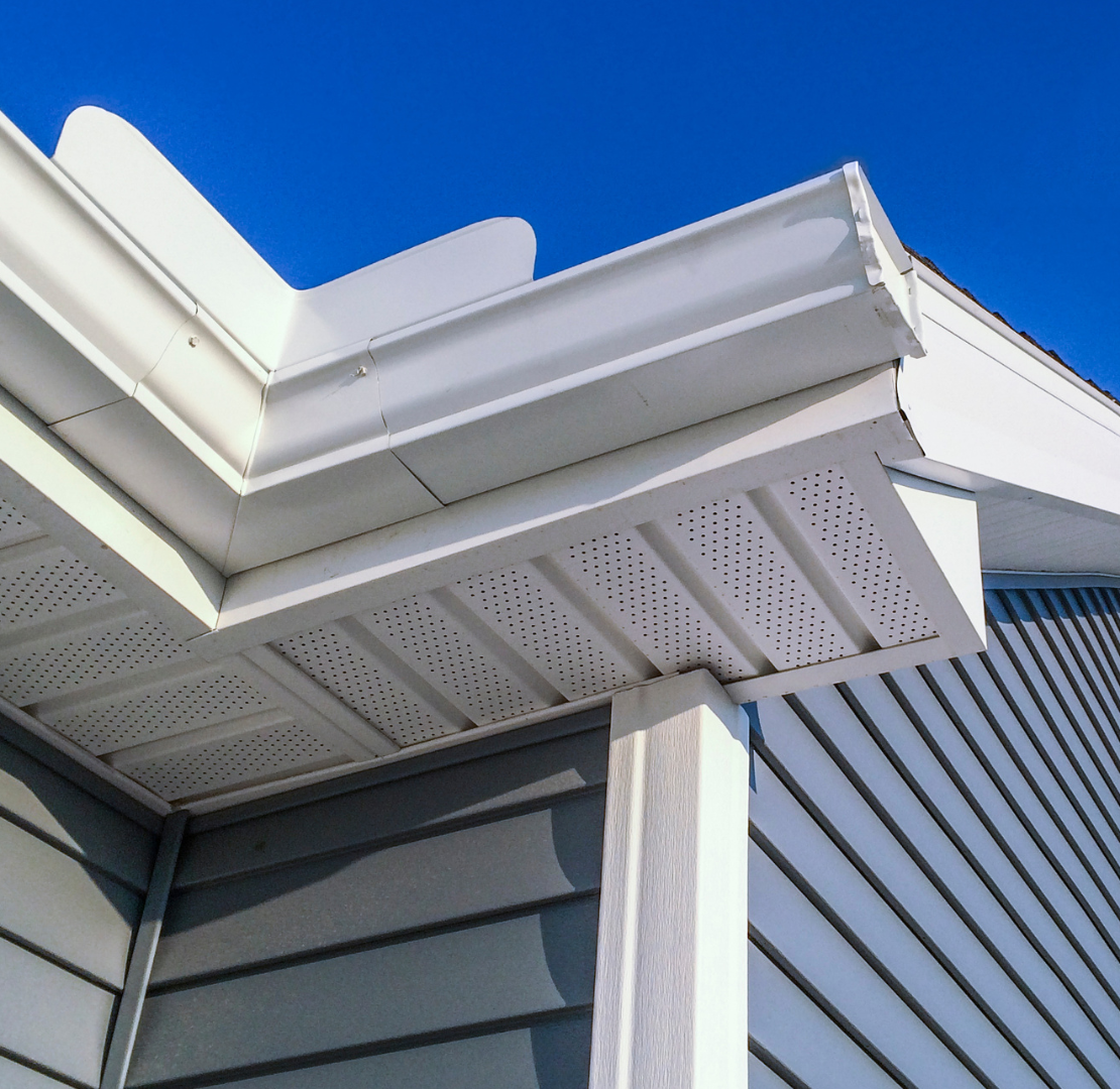 The roof of a house with a white gutter and a blue sky in the background.