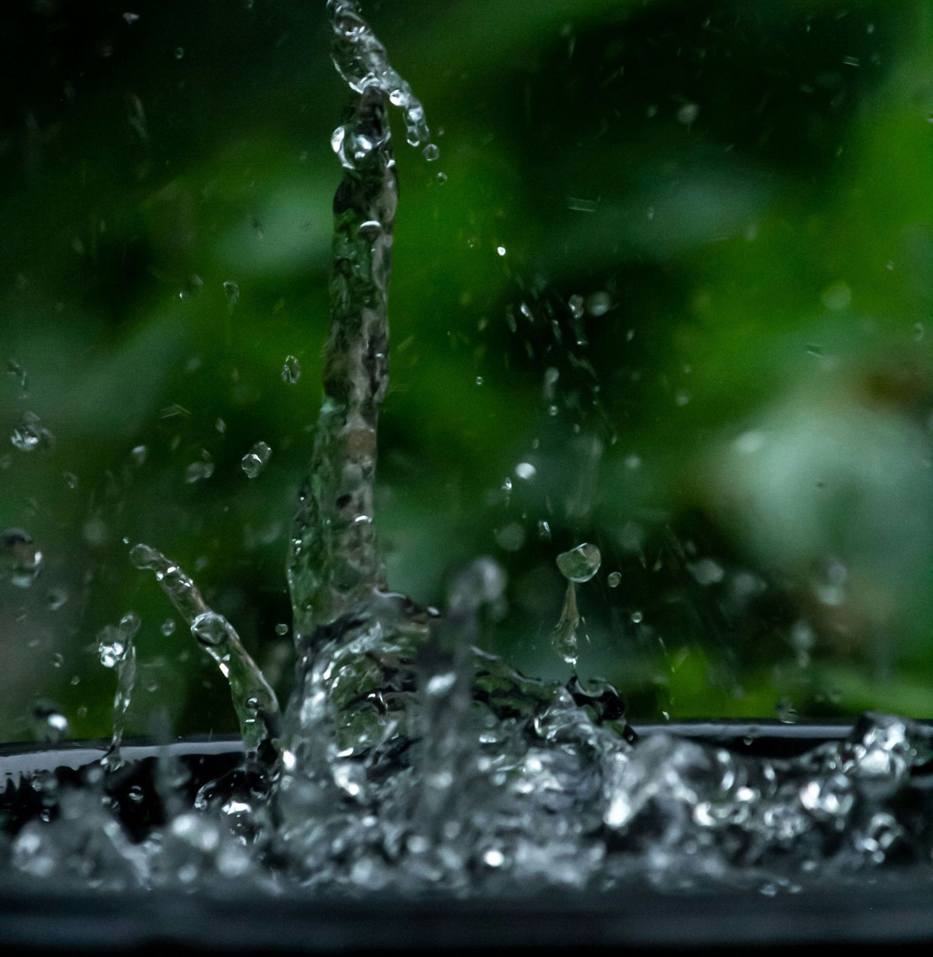 A close up of water splashing into a black bowl