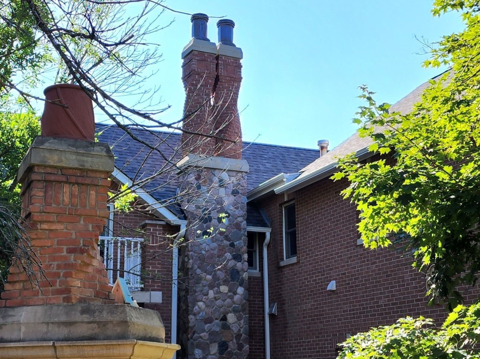 A brick house with two chimneys on the side of it.