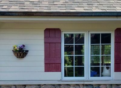 A white house with red shutters and a window.