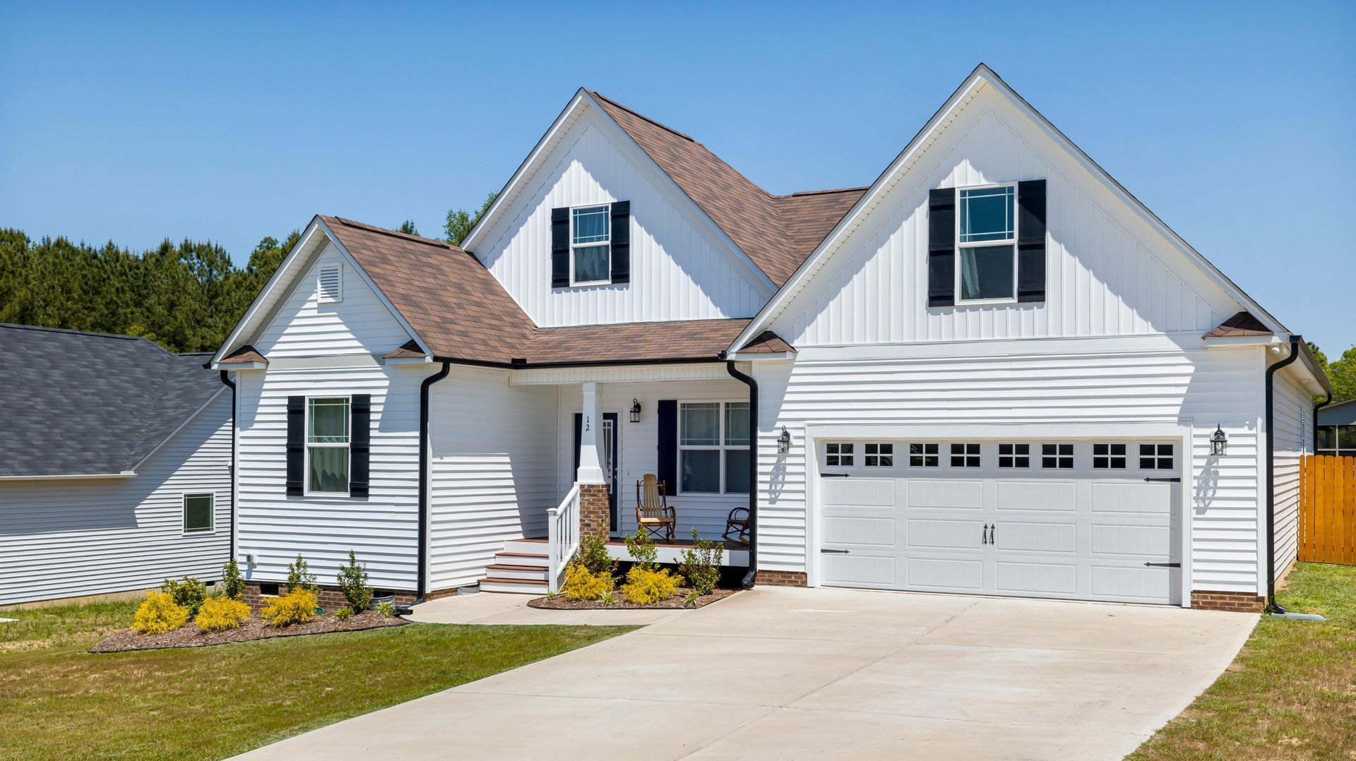 A white house with black shutters and a white garage door