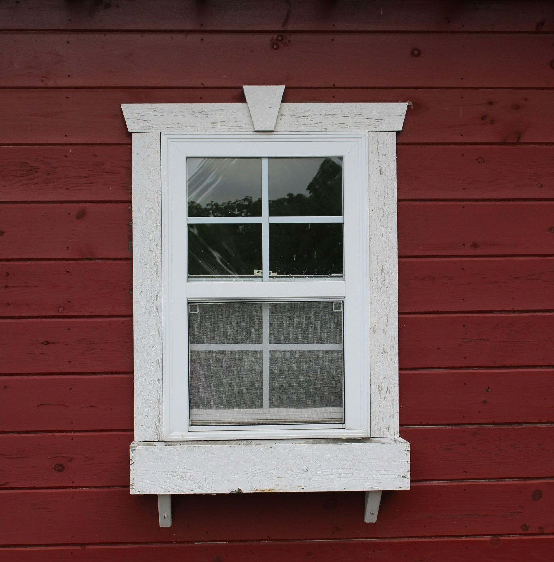 A window with a white frame on a red wall