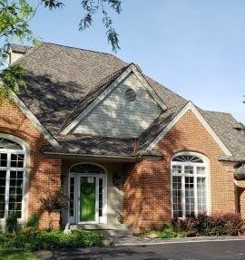 A large brick house with a green door and a gray roof.