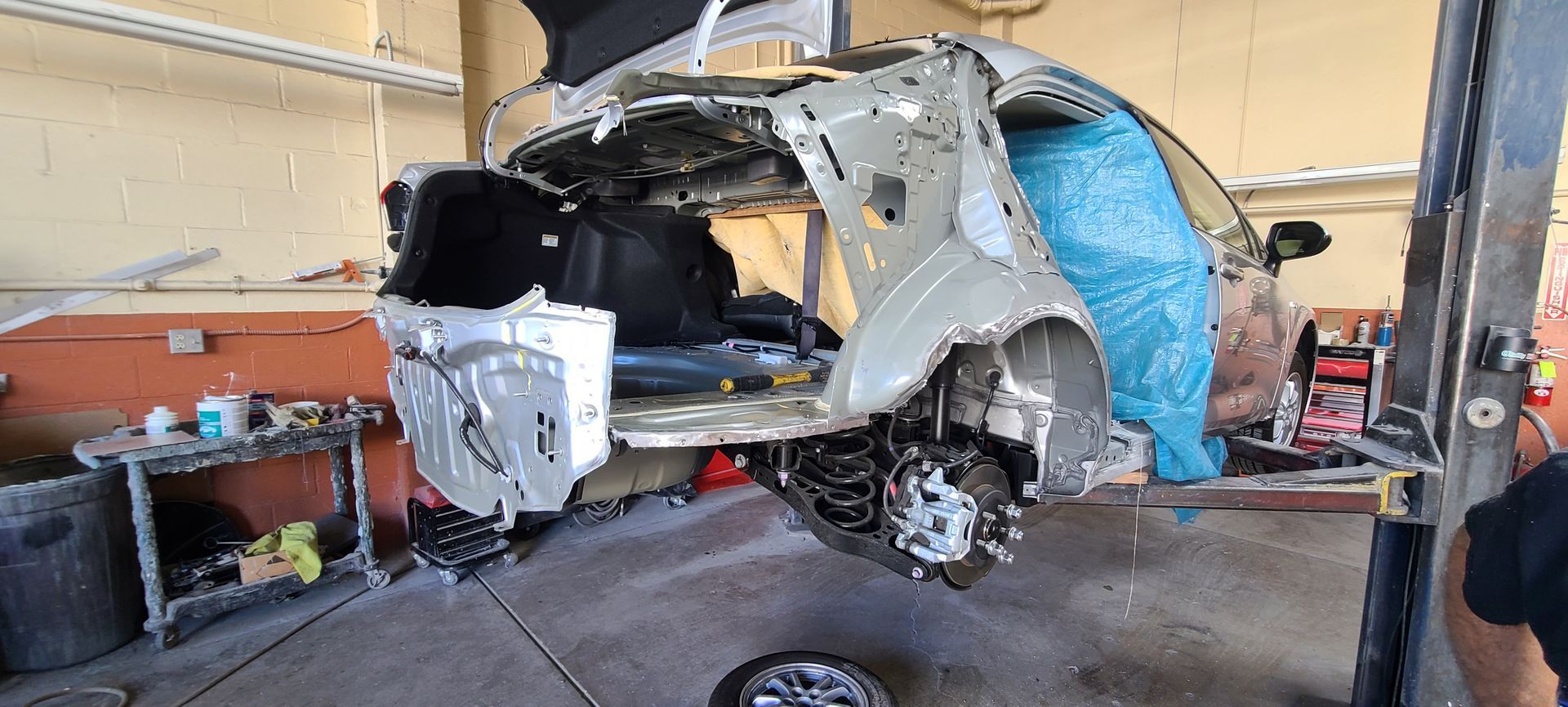 A car is being repaired on a lift in a garage.