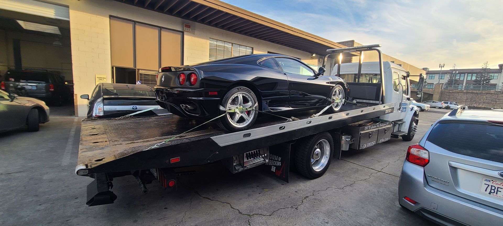 A black sports car is being towed by a tow truck.
