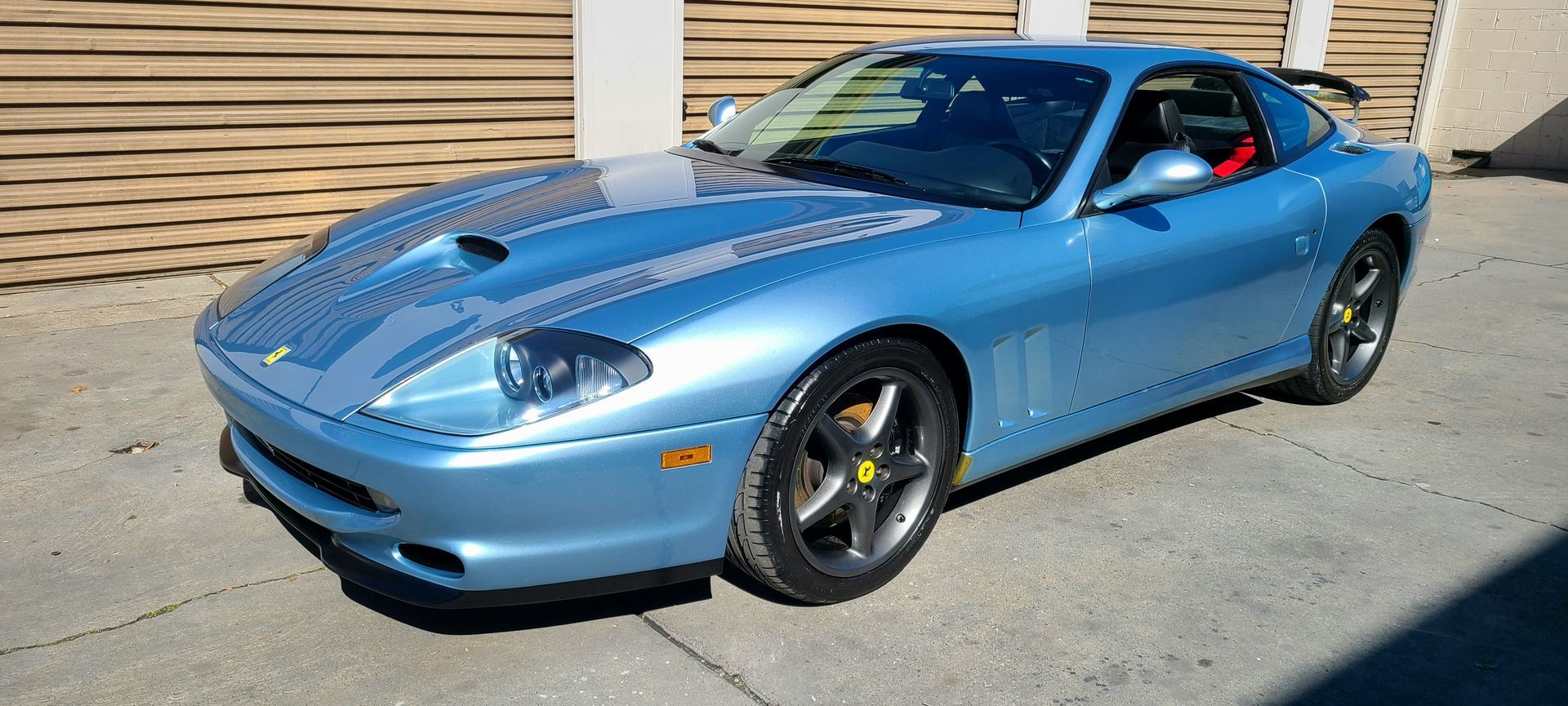 A blue ferrari sports car is parked in front of a building.
