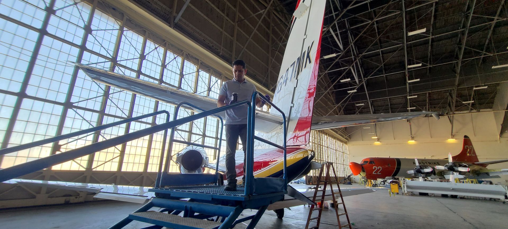 A man is working on a plane in a hangar.
