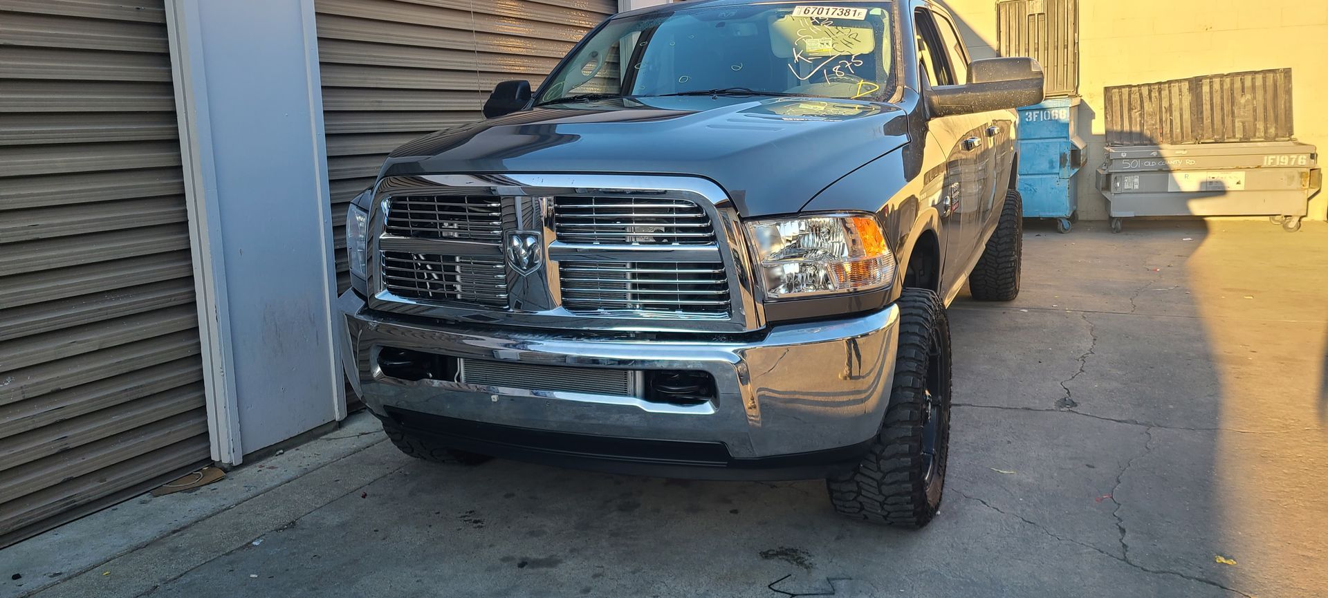 A blue dodge ram truck is parked in front of a building.