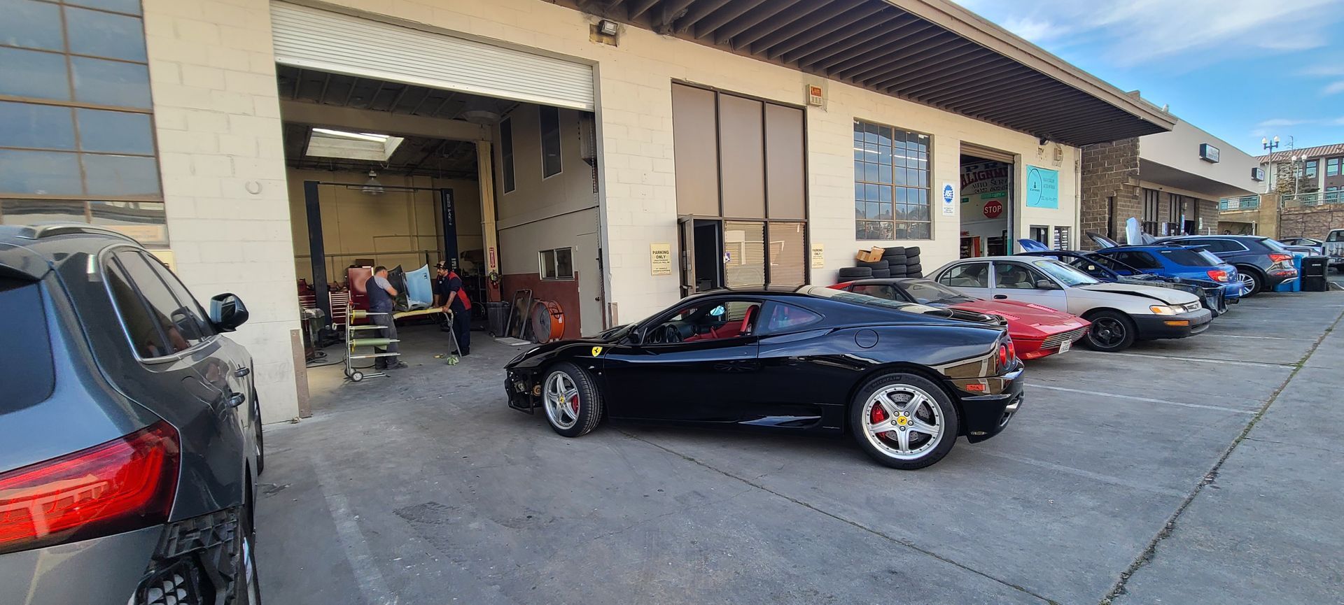 A row of cars are parked in front of a garage.