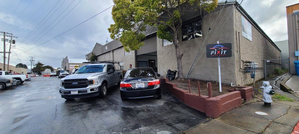 A truck and a car are parked in front of a building.