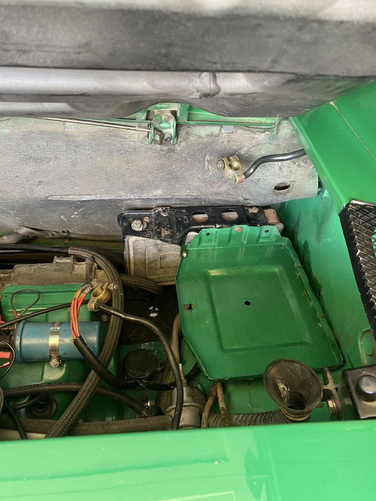The engine compartment of a green car with the hood open.