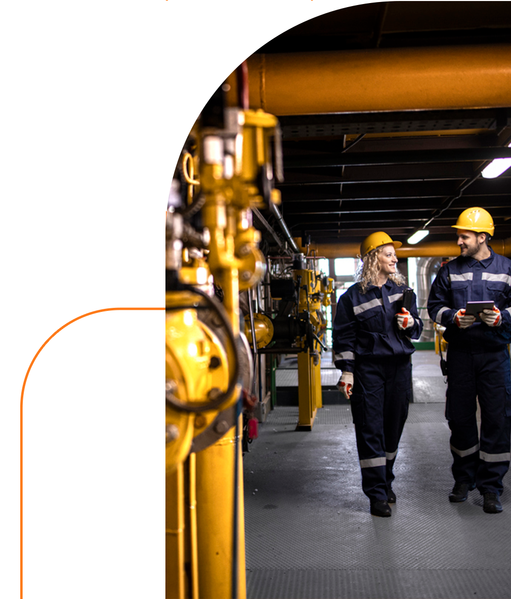 um homem e uma mulher usando capacetes estão andando em uma fábrica