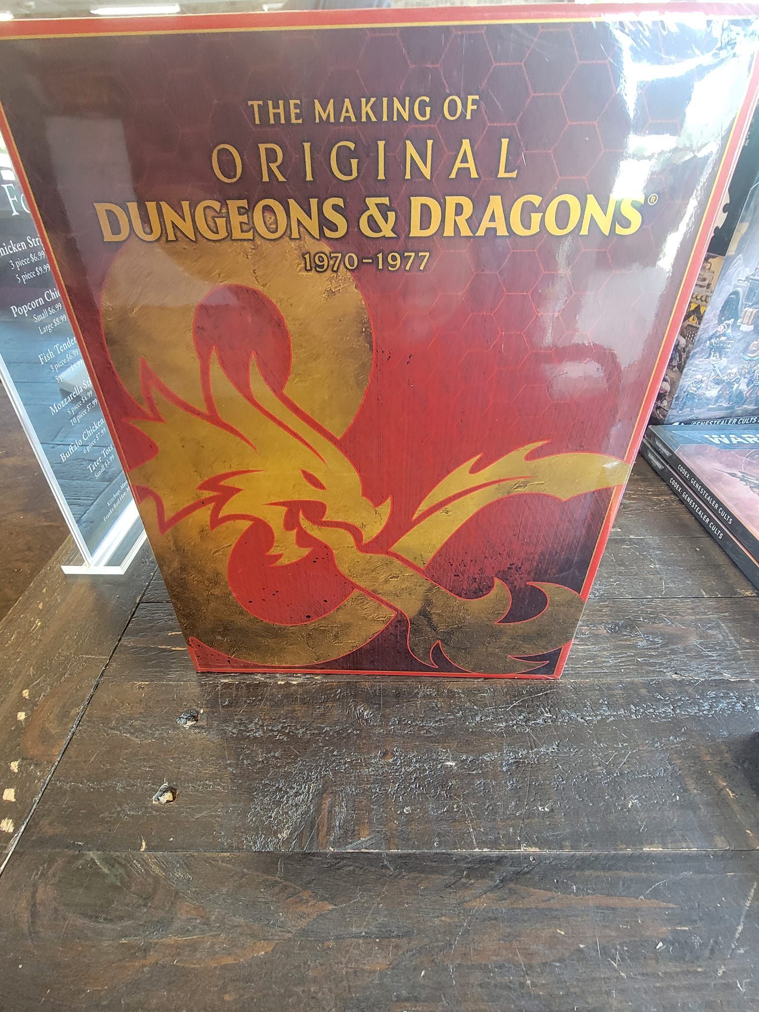 A book titled the making of original dungeons and dragons is sitting on a wooden table.