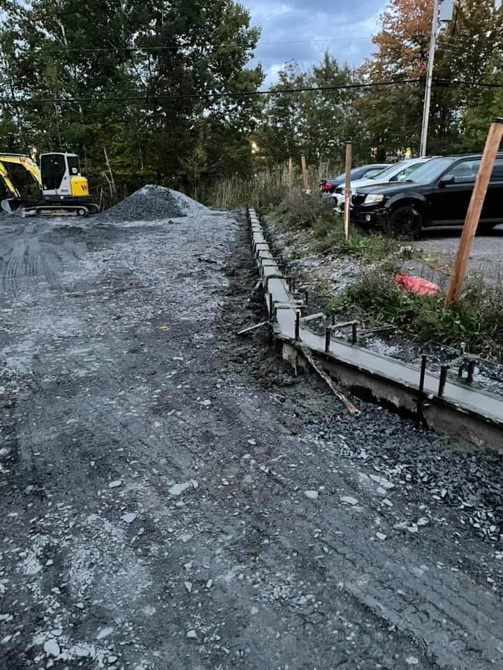 Un chantier de construction avec des voitures garées sur le bord de la route.