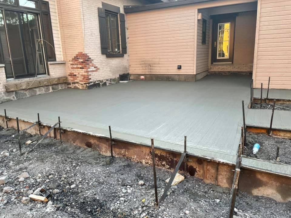 Une terrasse en béton est en cours de construction devant une maison.