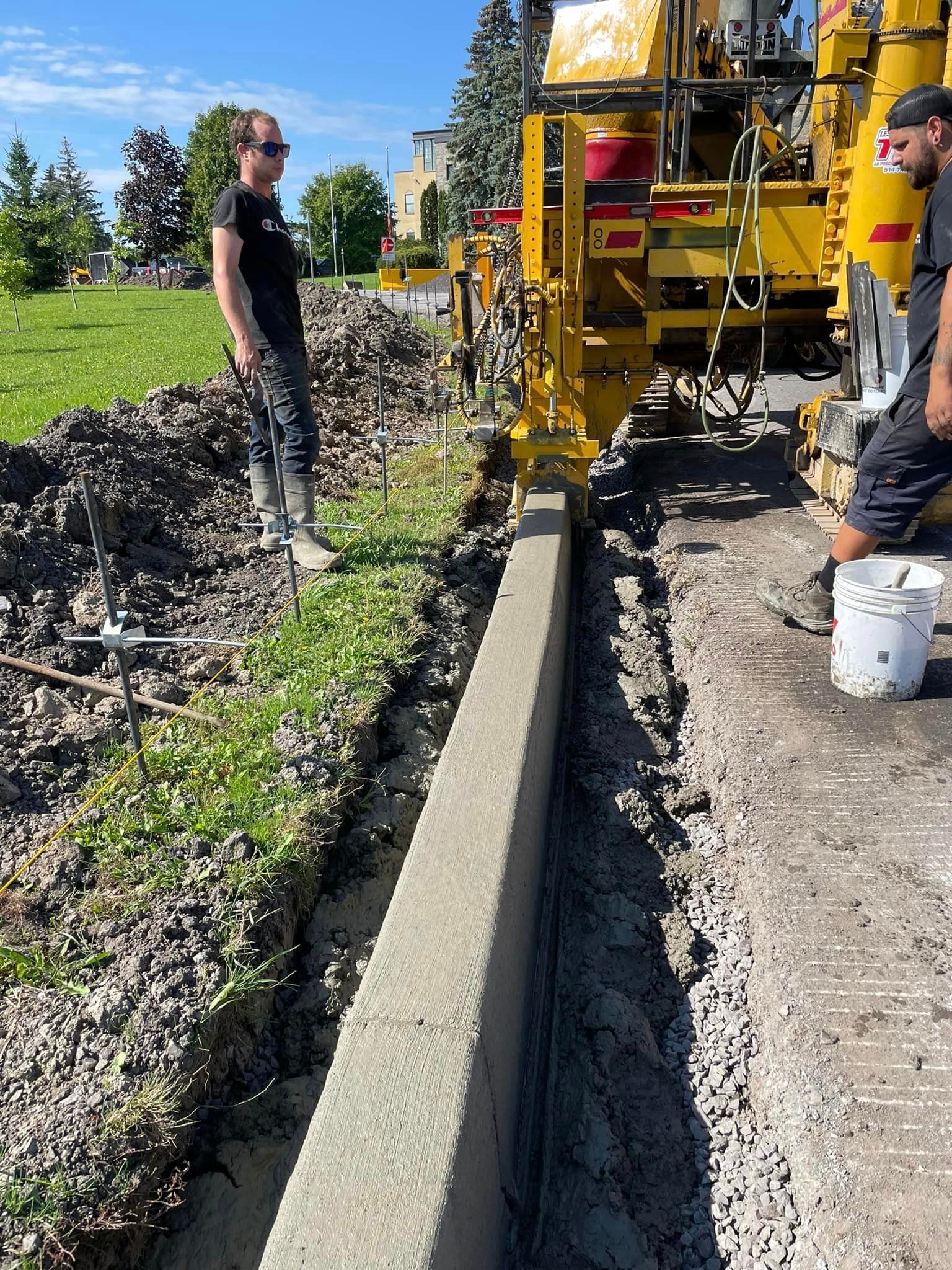 Un homme se tient à côté d’une machine qui pose du béton.