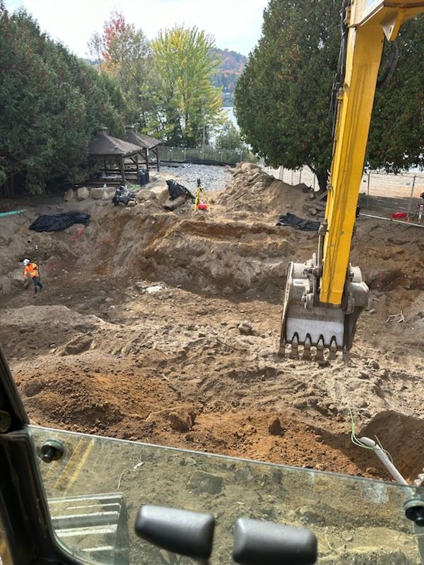 Une excavatrice jaune creuse un trou dans le sol.