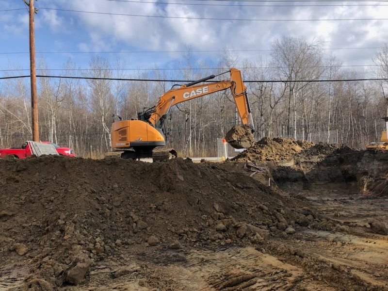 Un gros tas de terre est en train d'être excavé par une excavatrice.
