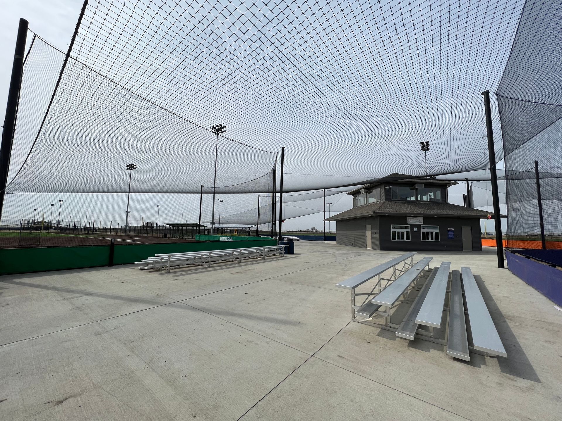 A baseball field with bleachers and a building in the background