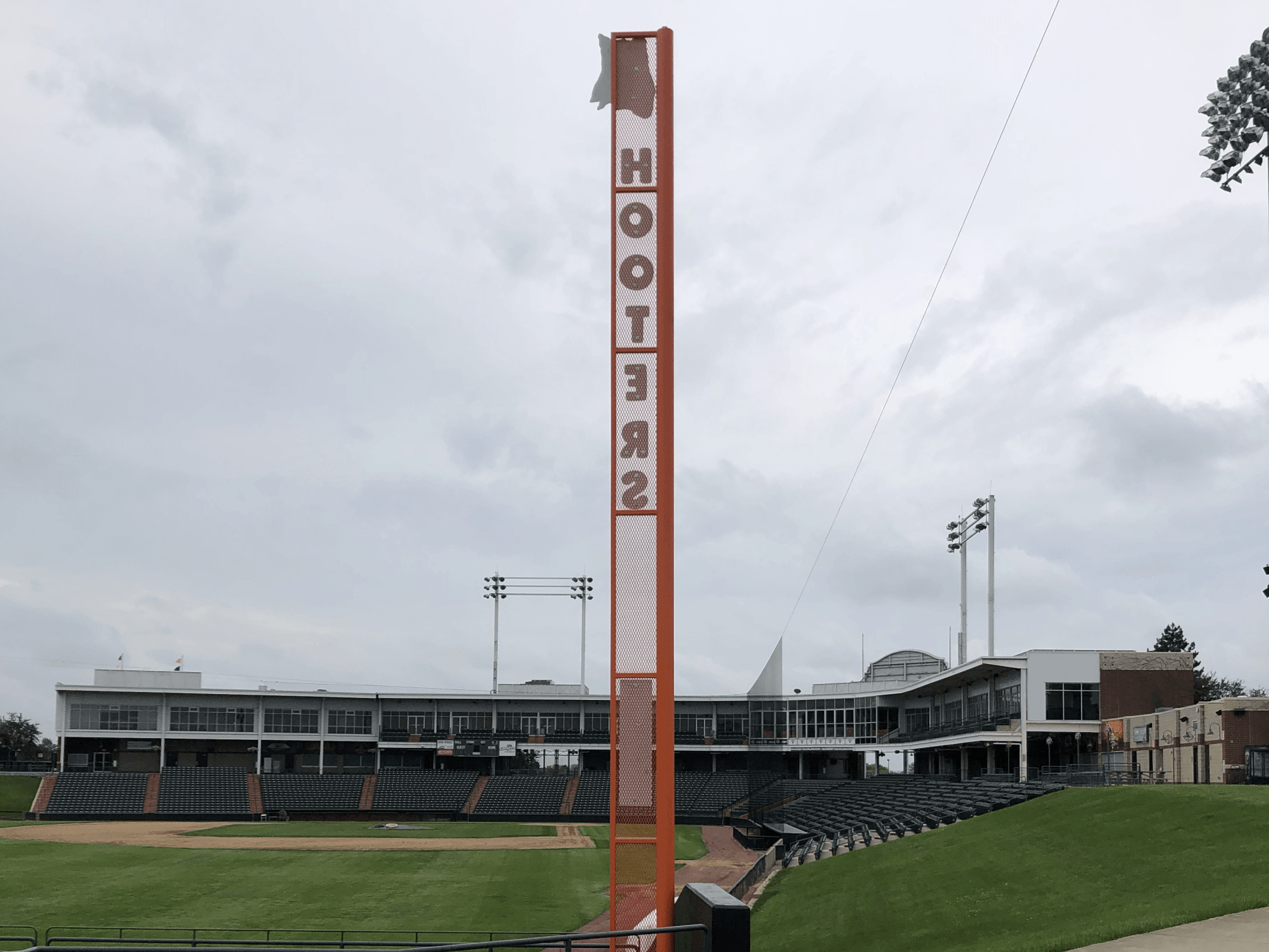 A baseball field with a hooters sign in the foreground