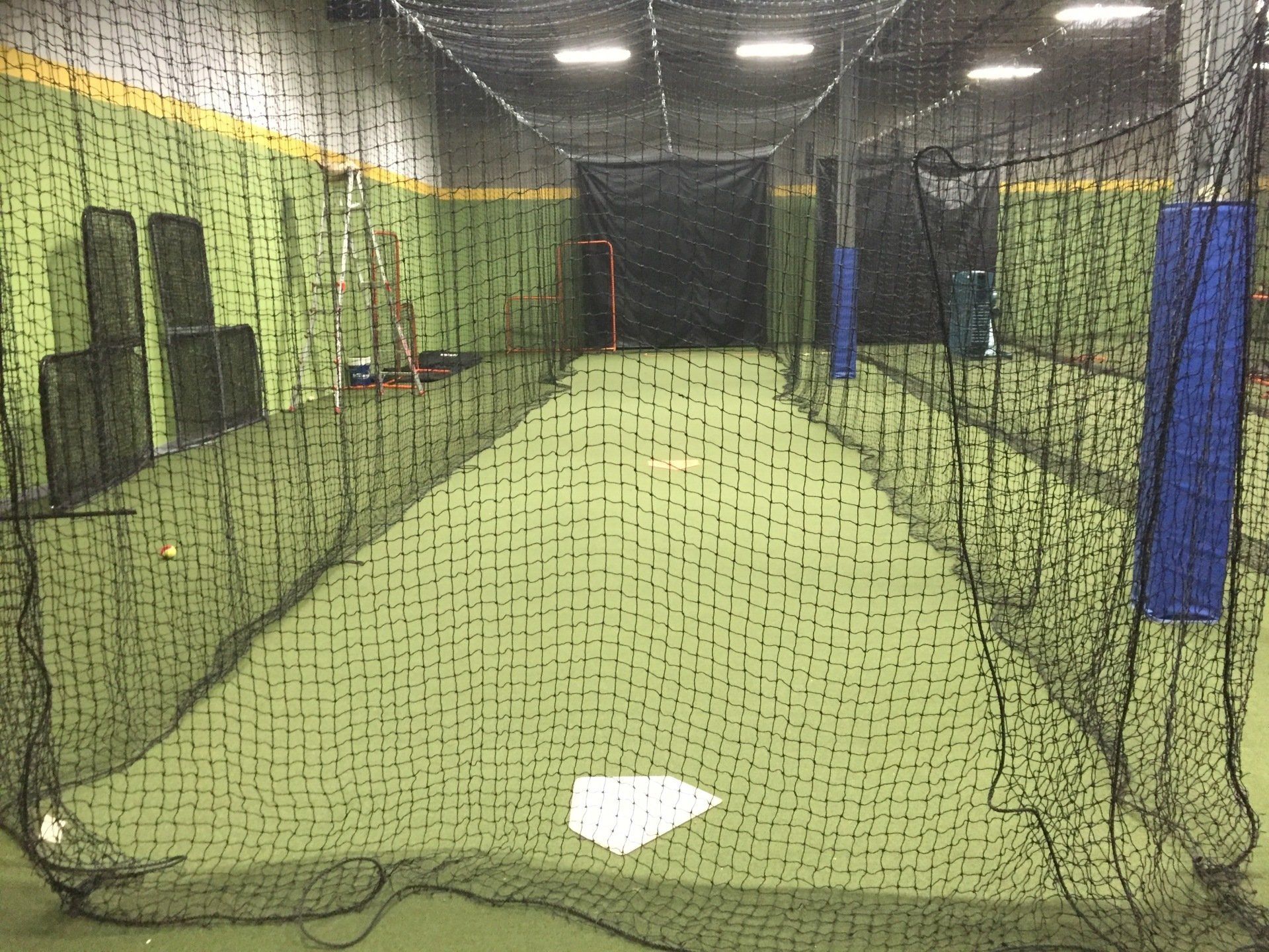 A baseball cage with a base in the middle of it.