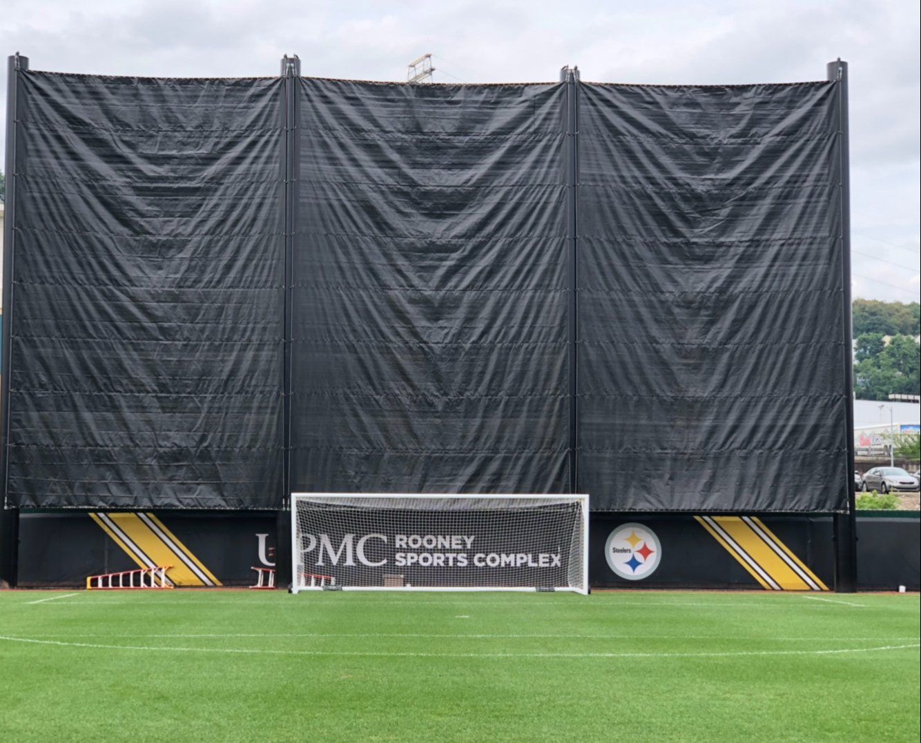 A soccer goal is sitting in front of a large black tarp.
