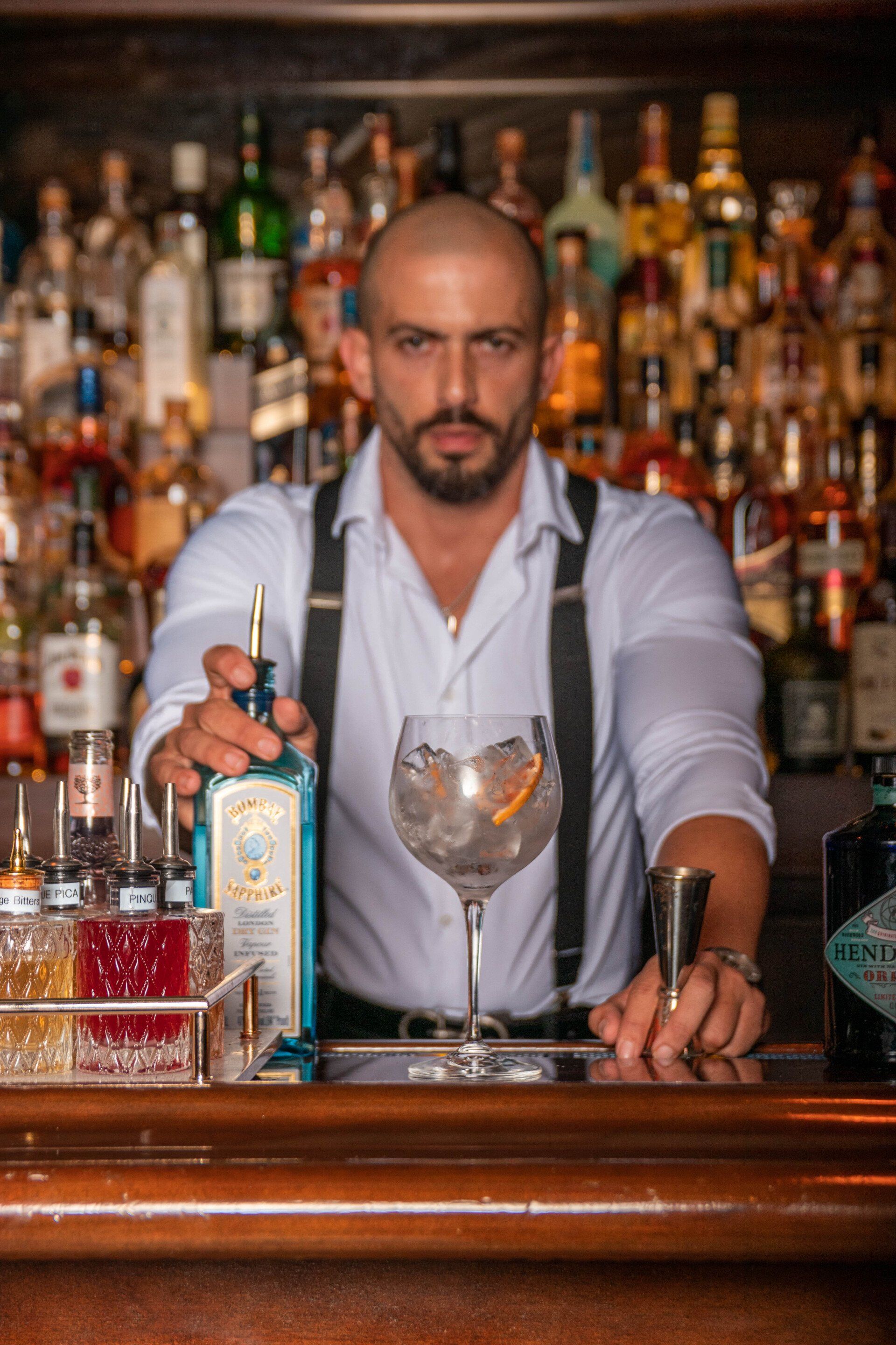 A bartender is pouring a drink into a glass at a bar.