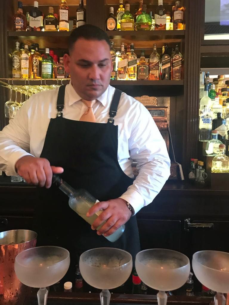A bartender is pouring a drink into a martini glass