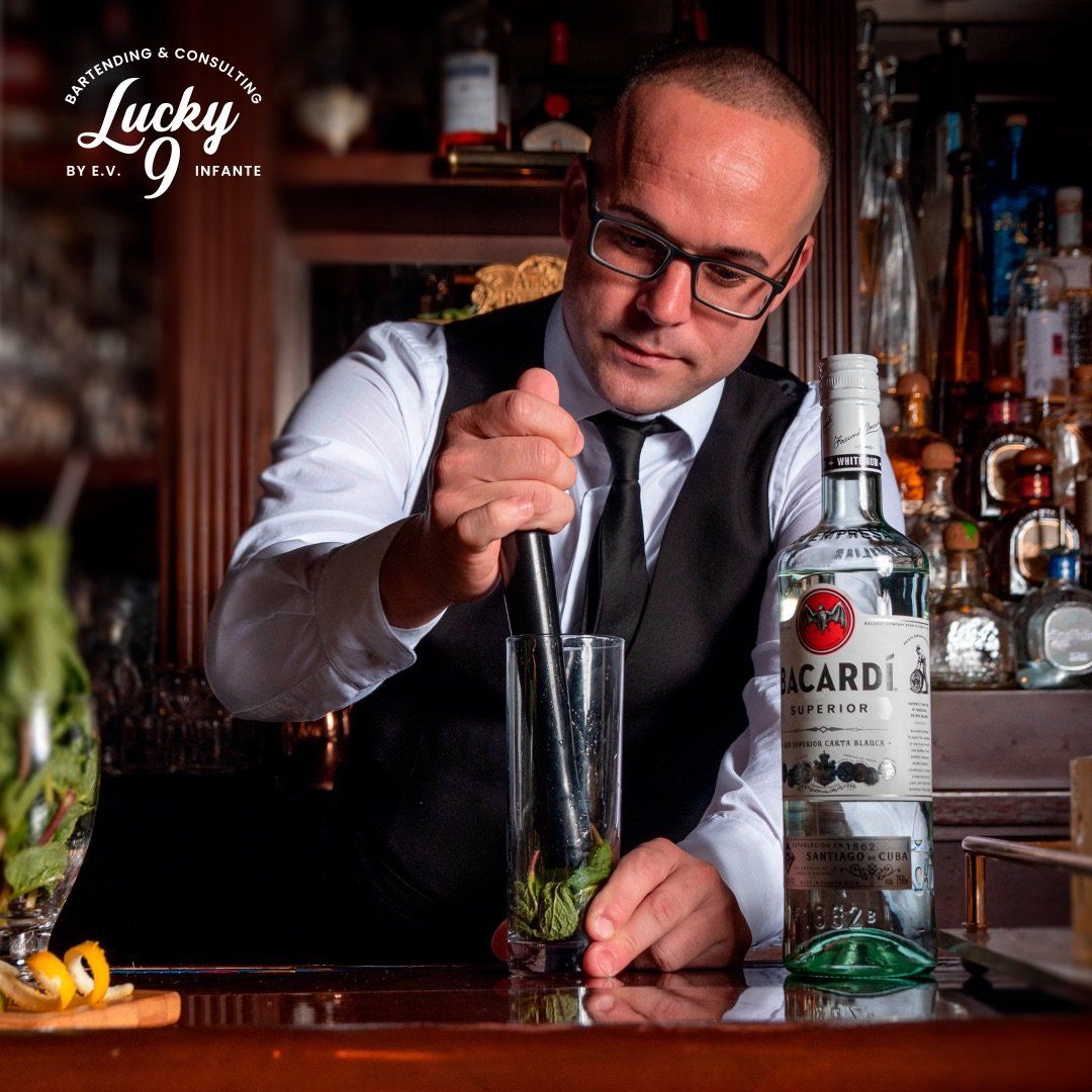 A bartender is preparing a drink with a bottle of bacardi in the background.