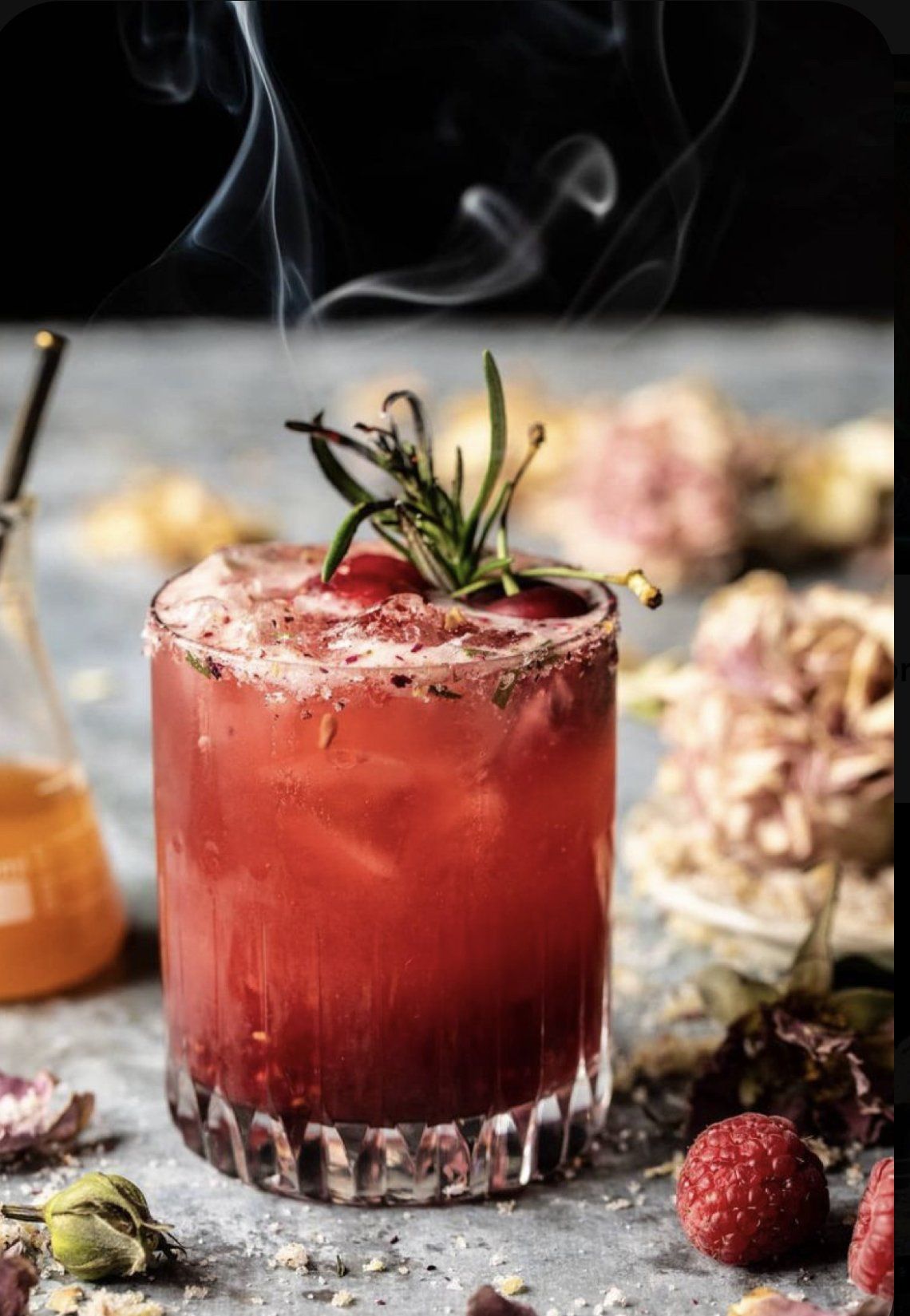 A close up of a red drink in a glass on a table.